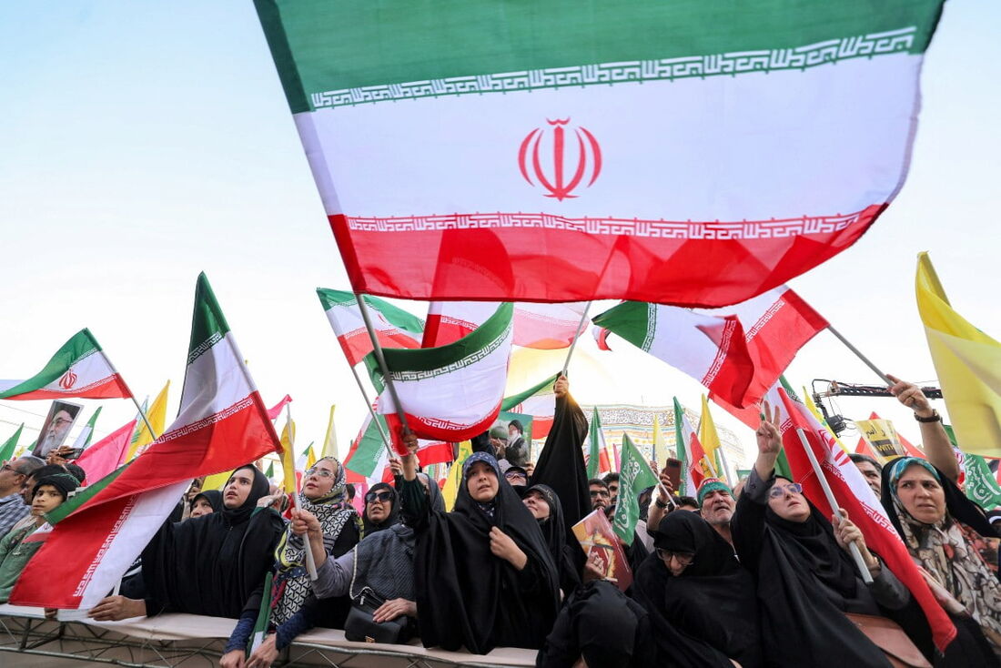 Manifestantes agitam bandeiras amarelas do Hezbollah libanês e do Irã enquanto se reúnem em um comício em solidariedade ao governo contra os ataques de Israel ao Irã. 