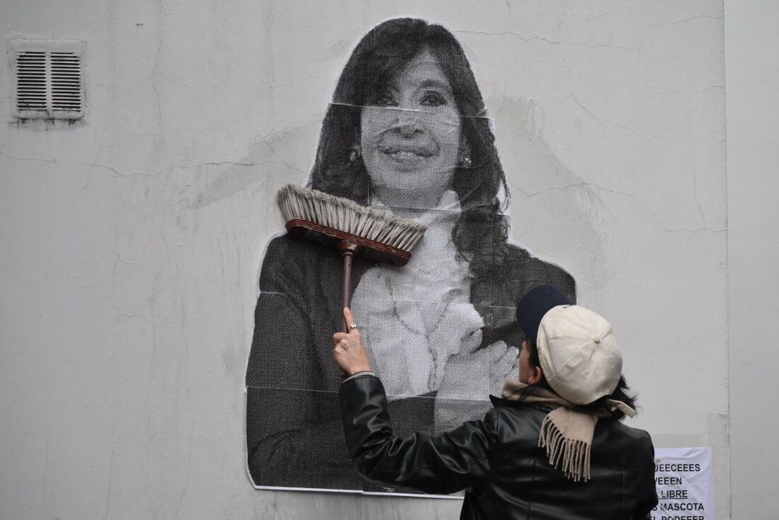 Um apoiador da ex-presidente argentina Cristina Fernández de Kirchner cola um cartaz em frente à sua residência em Buenos Aires.