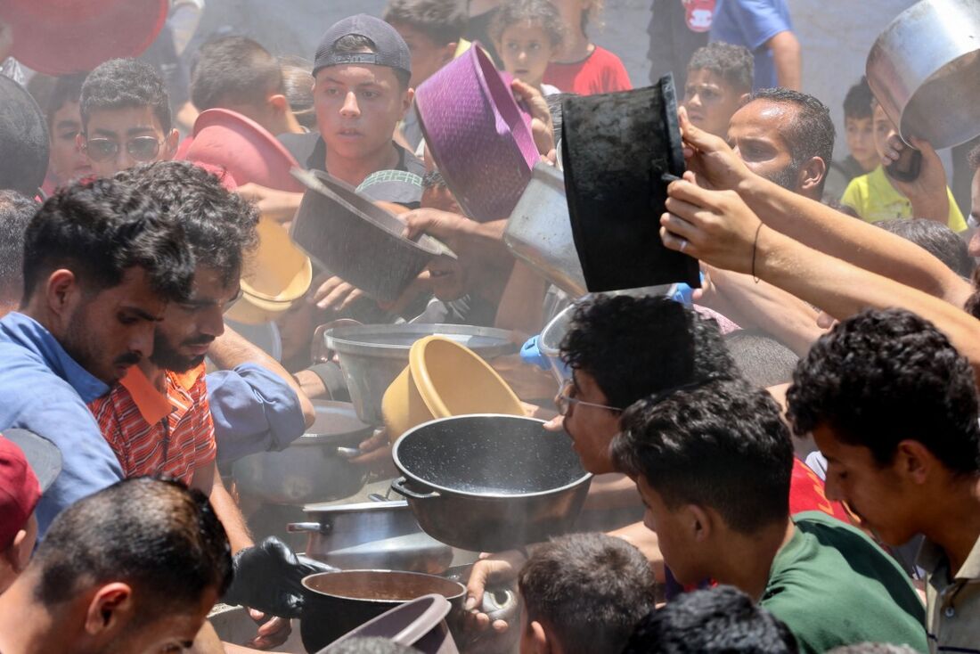 Grupo de palestinos tentando conseguir comida em um centro de distribuição de ajuda humanitária