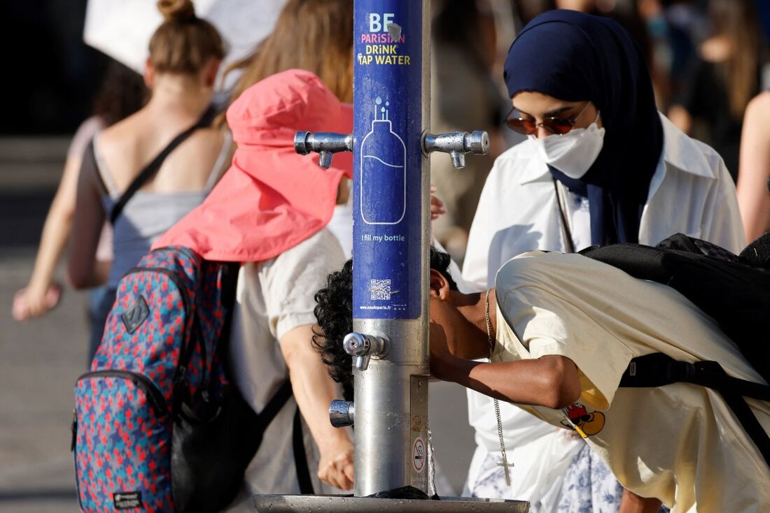 Pessoas se refrescam em uma fonte pública durante uma onda de calor em Paris, em 30 de junho de 2025. 