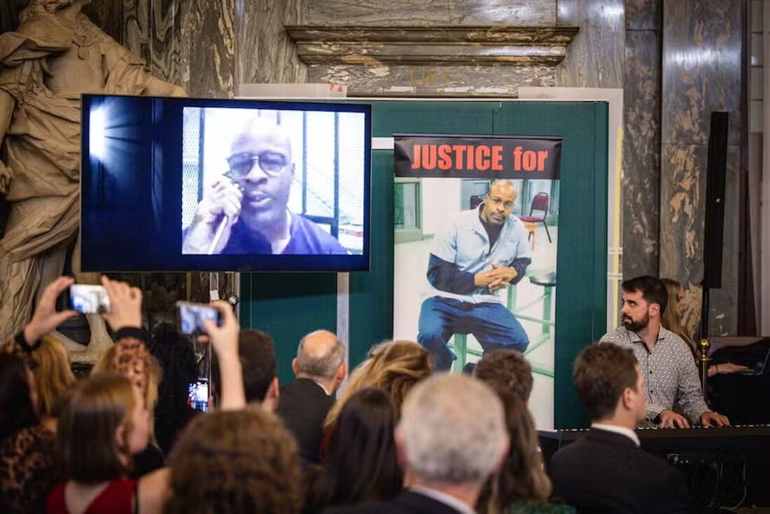 O pianista de jazz espanhol Albert Marques (D) olha para um vídeo do americano Keith LaMar tocando por meio de um telefone amplificado da Penitenciária Estadual de Ohio, nos EUA, onde ele é condenado à morte.