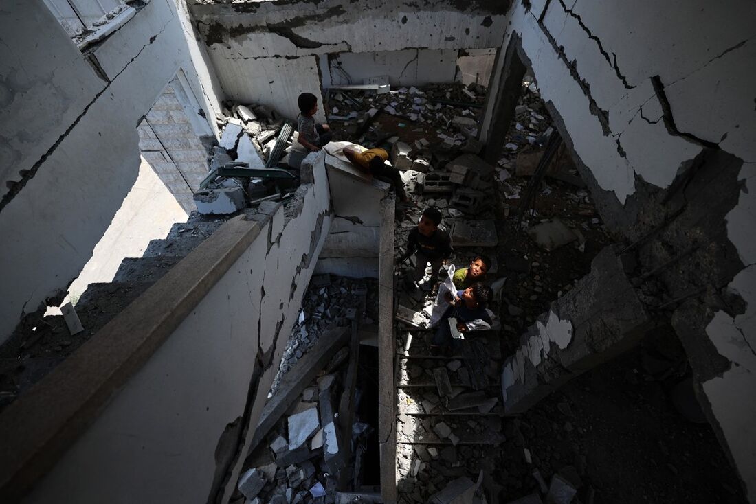 Meninos palestinos recuperam livros e páginas do Alcorão, o livro sagrado do islamismo, enquanto inspecionam os escombros após um ataque israelense atingir a Mesquita Ansar