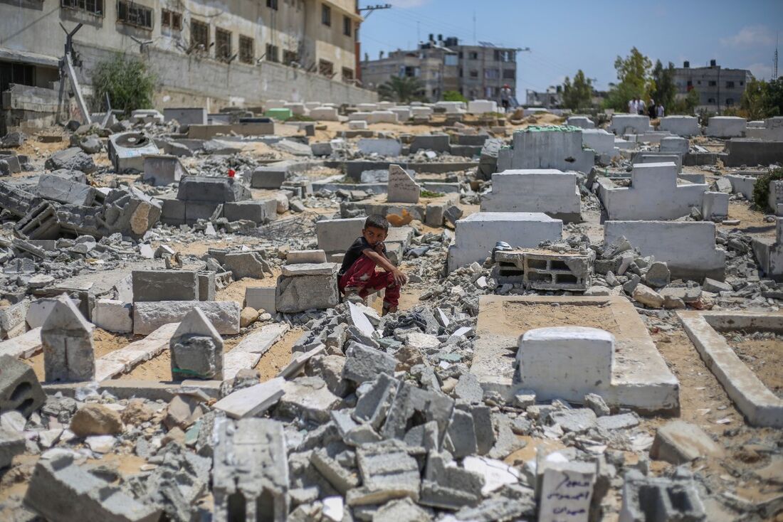 Palestinos visitam túmulos danificados após um ataque israelense que atingiu a Mesquita Ansar e o cemitério adjacente em Deir el-Balah, no centro da Faixa de Gaza