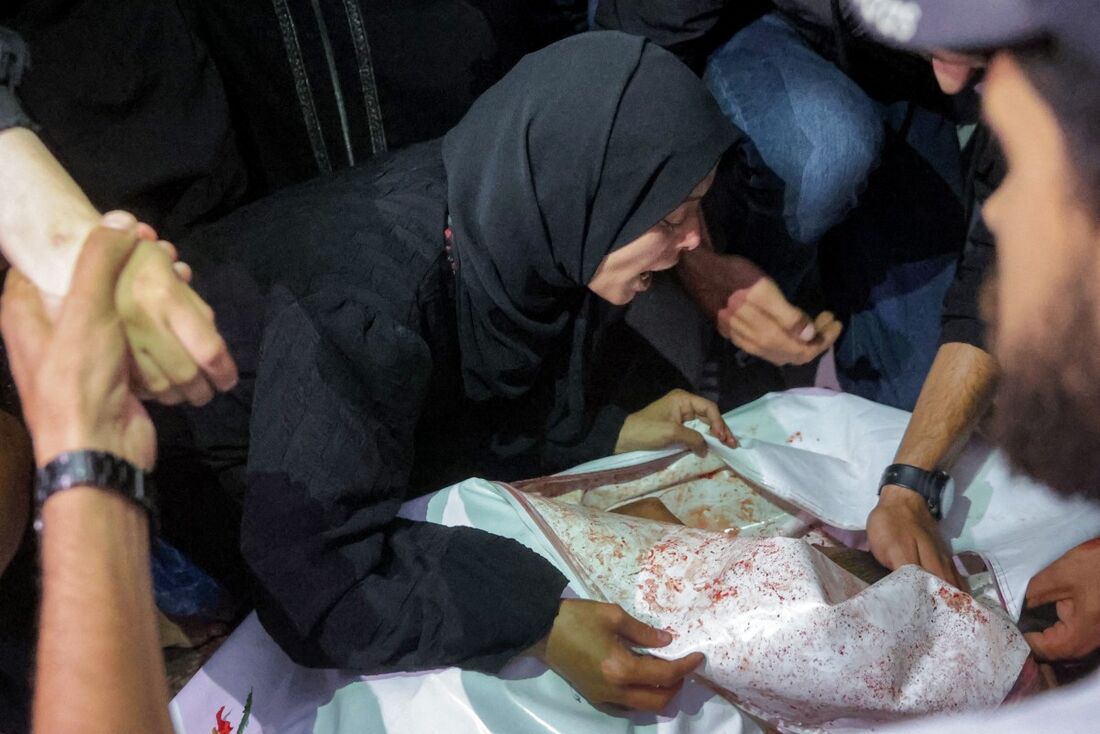 Mulher chora ao lado do corpo do fotojornalista palestino Moamen Abu Alouf
