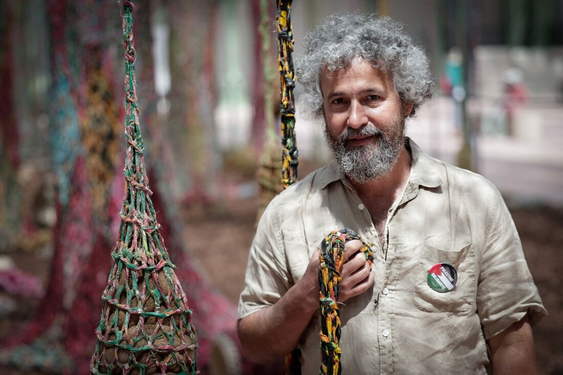O artista brasileiro Ernesto Neto posa para uma fotografia ao lado de sua instalação artística "Nosso Barco Tambor Terra", no Grand Palais d'Eté, em Paris, em 10 de junho de 2025.