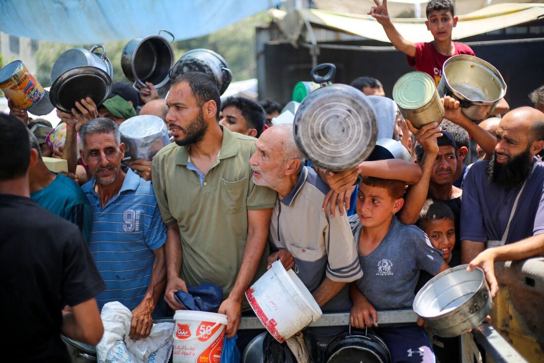 Palestinos esperam por comida em um ponto de distribuição em Nuseirat, no centro da Faixa de Gaza