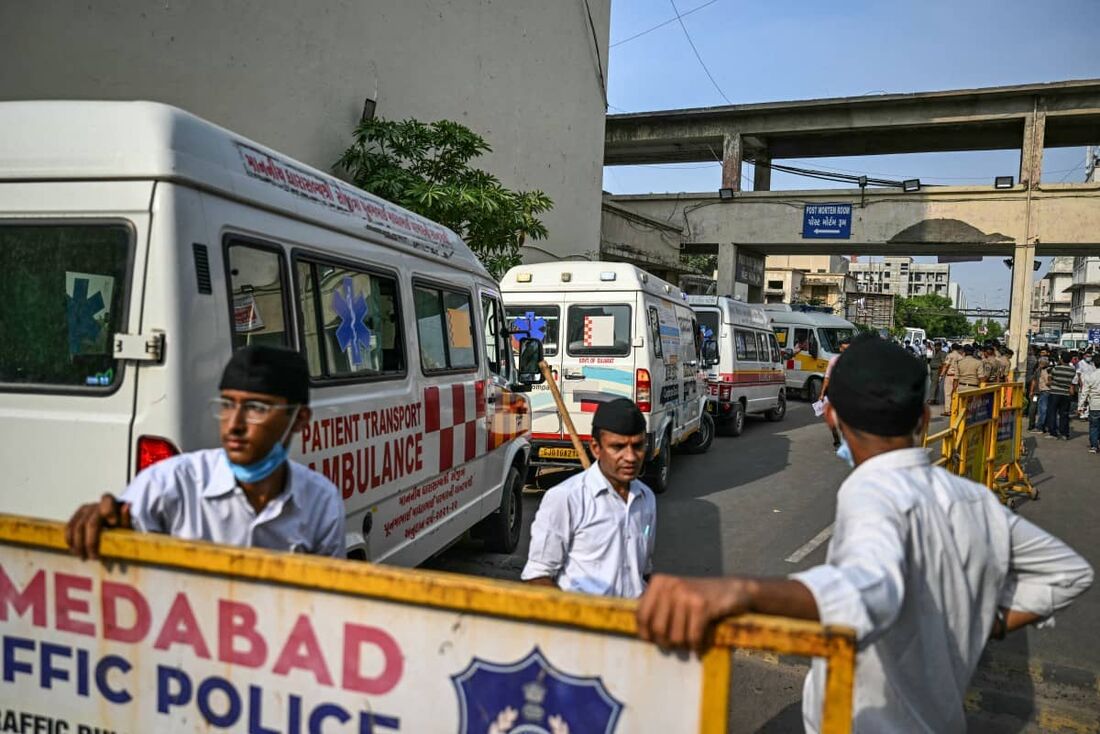 Ambulâncias perto da sala de necropsia de um hospital antes de transferir os corpos das vítimas para um necrotério em Ahmedabad