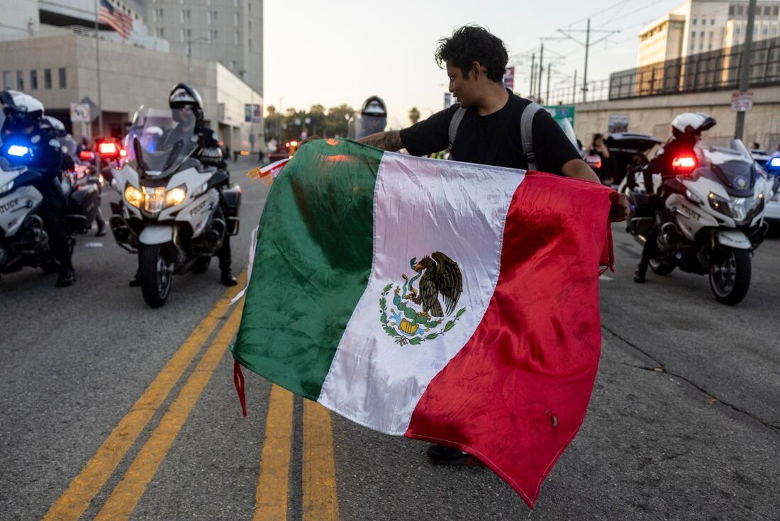Imigrante segura a bandeira do México em protestos contra a repressão migratória em Los Angeles