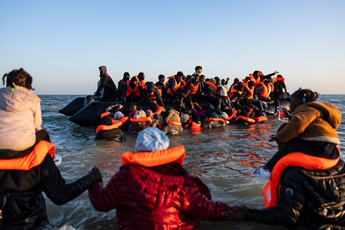 Migrantes tentam embarcar no barco de um contrabandista na tentativa de cruzar o Canal da Mancha na praia de Gravelines, no norte da Frana