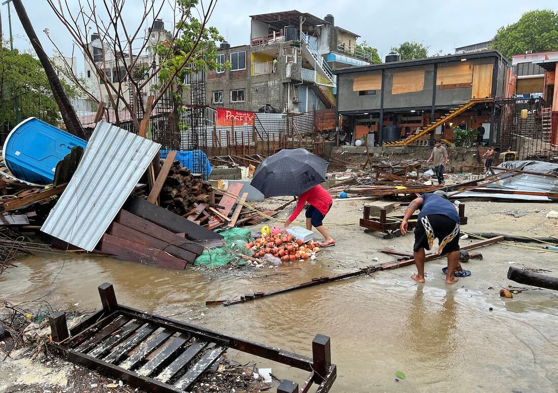Moradores caminham entre os destroços após a passagem do furacão Erick em Bahia Principal, Puerto Escondido, estado de Oaxaca, México