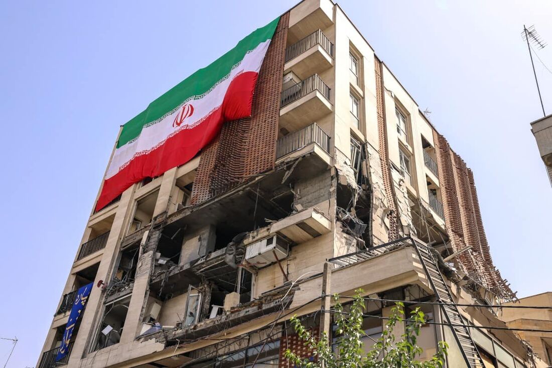 Edifício residencial que foi atingido por um ataque israelense coberto com uma grande bandeira iraniana, em Teerã