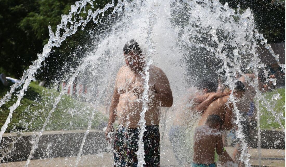 Pessoas se refrescam sob fontes de água na área de recreação Madrid Rio durante a primeira onda de calor do verão em Madri