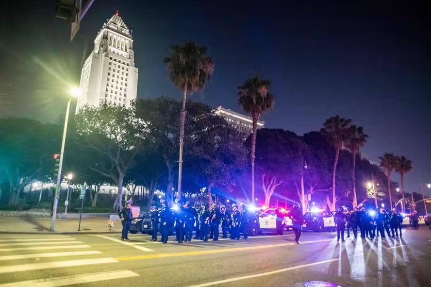 Policiais com equipamento antimotim cercam área da Prefeitura de Los Angeles durante o toque de recolher, após dias de protestos em resposta às operações do governo Trump contra imigrantes 