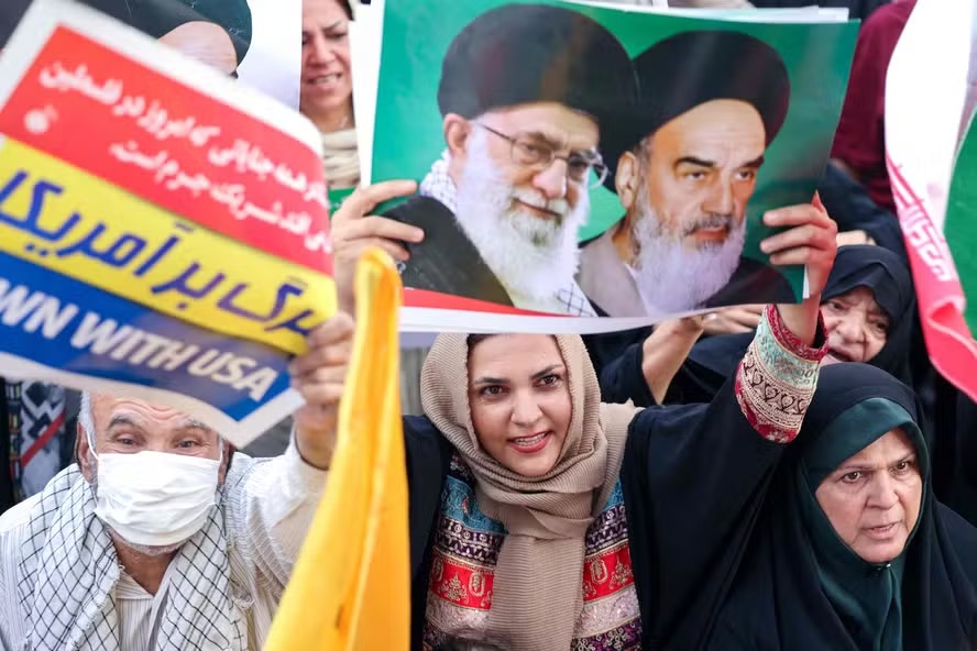 Iraniana segura cartaz com retratos do líder supremo Ali Khamenei e do falecido aiatolá Khomein