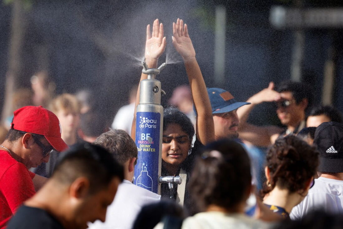 Pessoas se refrescando em fonte pública durante uma onda de calor em Paris