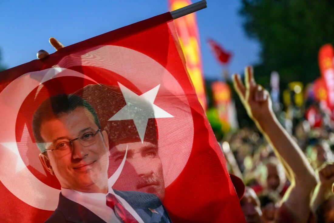 Um apoiador segura uma bandeira do prefeito detido de Istambul, Ekrem Imamoglu, e do primeiro presidente da República da Turquia, Mustafa Kemal Ataturk