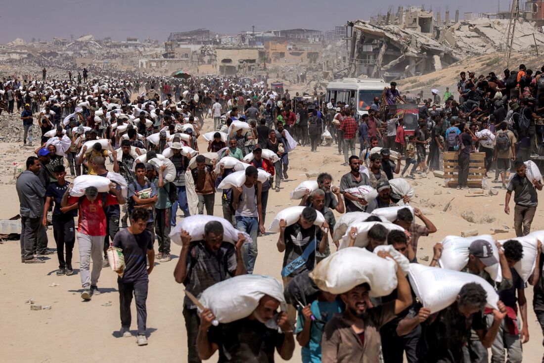 Palestinos caminham com sacos de farinha