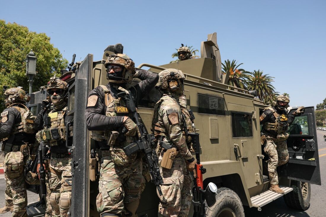 Agentes federais da Alfândega e Patrulha de Fronteira dos EUA (CBP) viajam em um veículo blindado dirigindo lentamente pela Wilshire Boulevard, perto do Parque MacArthur, em Los Angeles, Califórnia