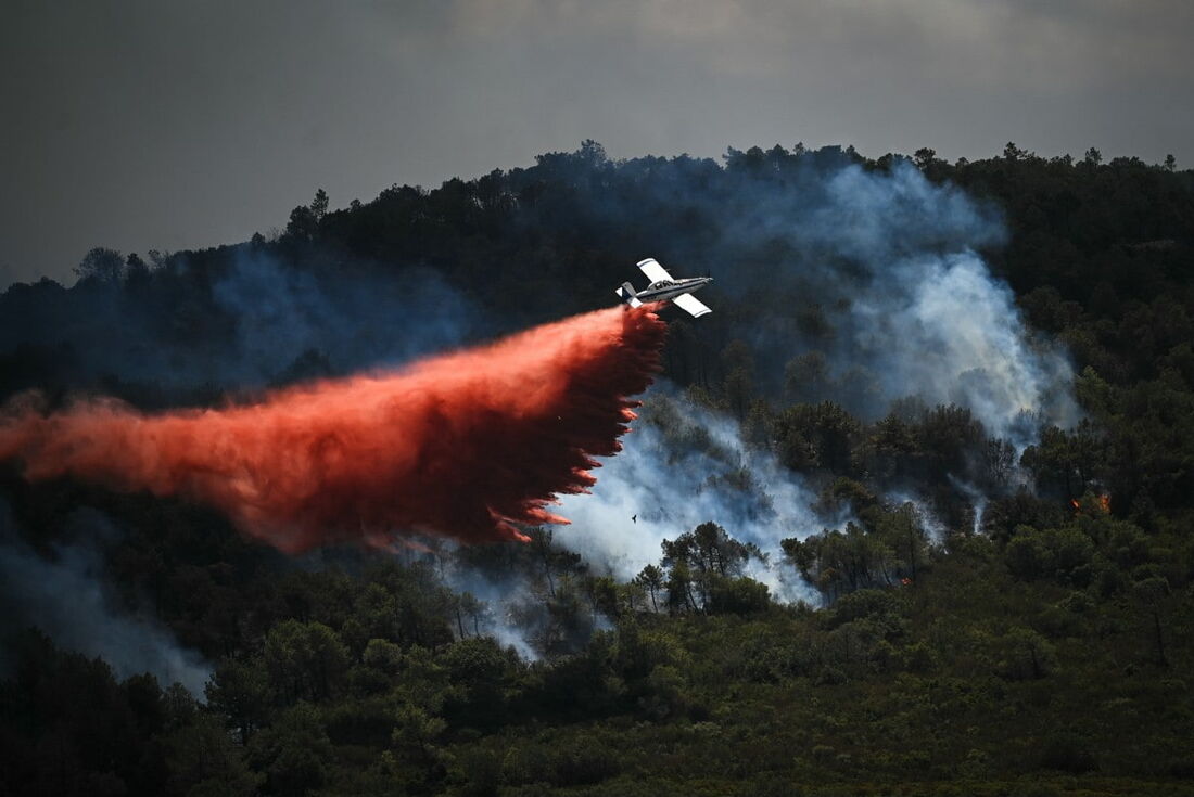 Um avião de combate a incêndios Air Tractor AT-802 lança retardante de fogo sobre um incêndio florestal perto do bairro de Aussieres