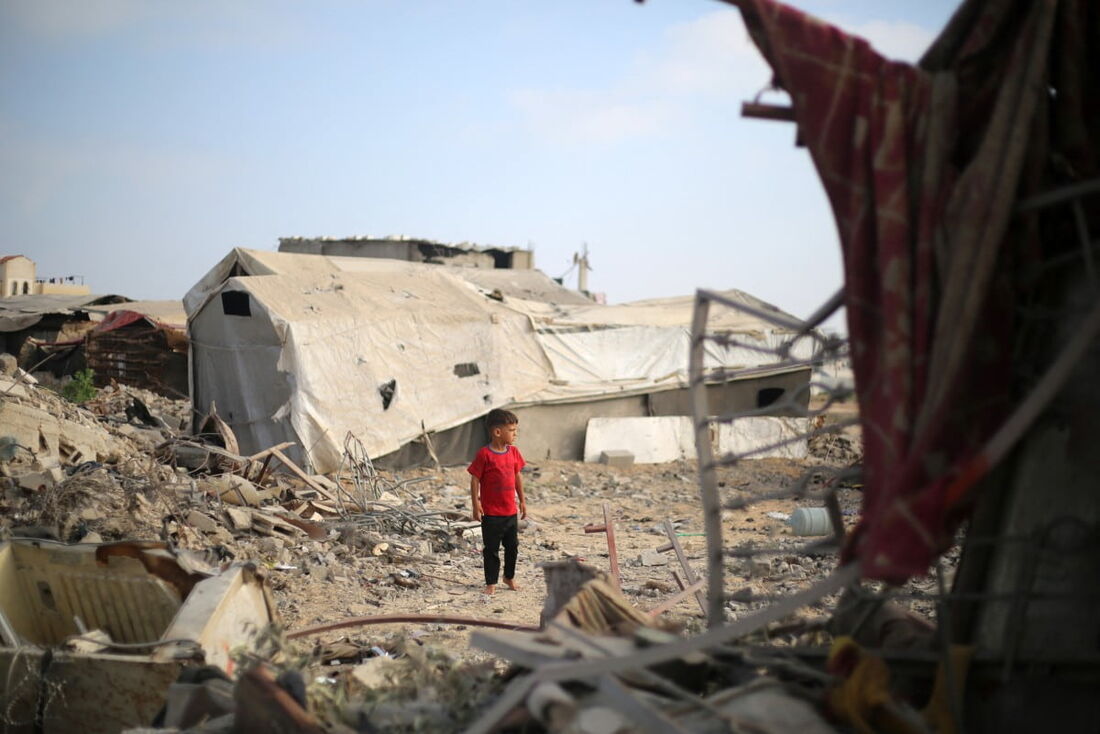 Um menino palestino em meio à destruição após um ataque israelense no campo de refugiados de Bureij