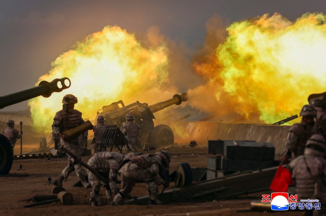 Soldados das unidades de artilharia disparando projéteis contra o mar