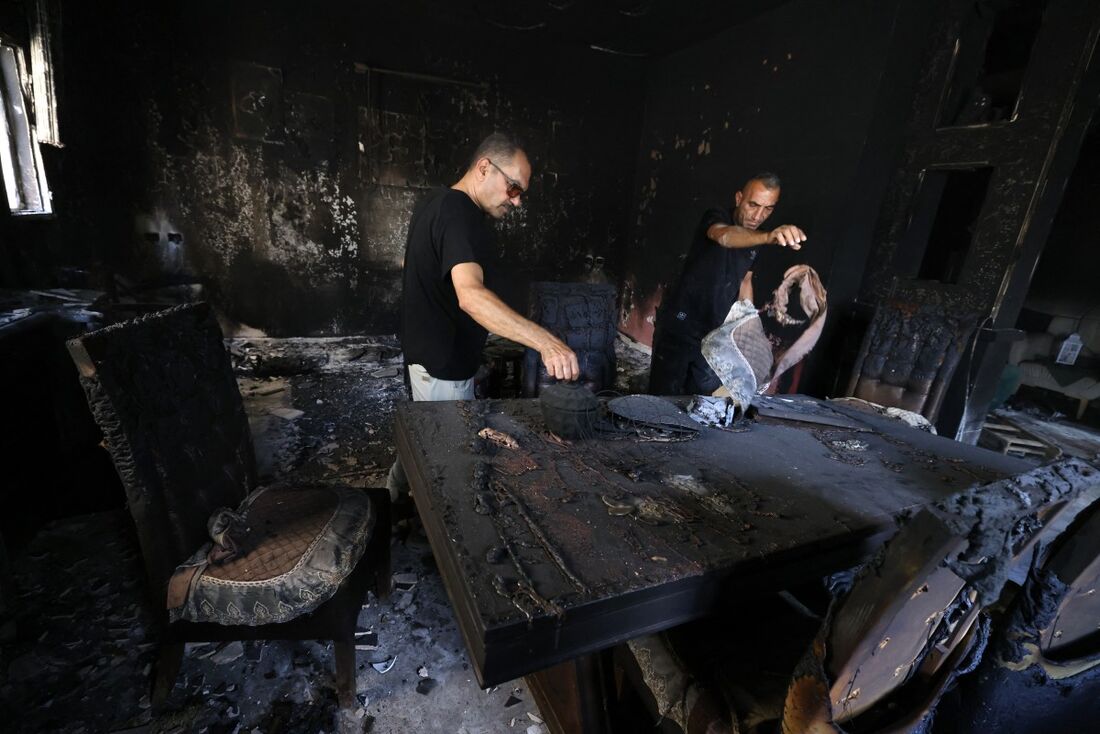 Homens inspecionam os danos causados pelo incêndio em uma casa no campo de refugiados palestinos de Nur Shams, a leste de Tulkarem, na Cisjordânia ocupada por Israel 