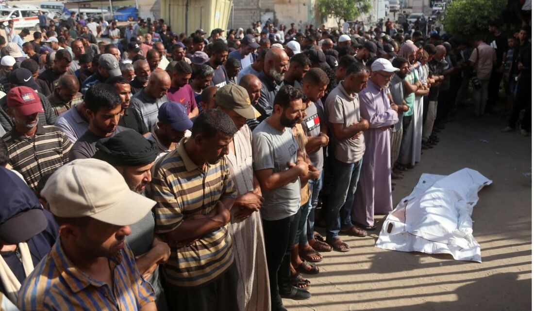 Pessoas em luto rezam junto aos corpos das vítimas que foram mortas no dia anterior pelo bombardeio israelense