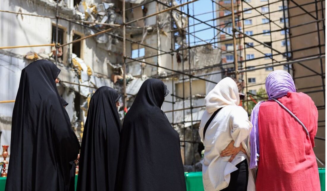 Mulheres olham fotos e brinquedos de crianças mortas em um ataque aéreo israelense no complexo residencial de Chamran