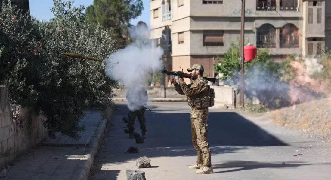 Membro das forças de segurança sírias dispara uma arma durante confrontos no sul de Sweida 