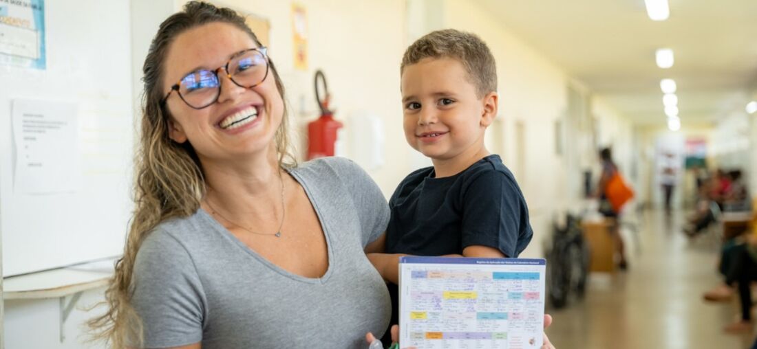 Moça com criança no colo para recebimento de imunização da meningite