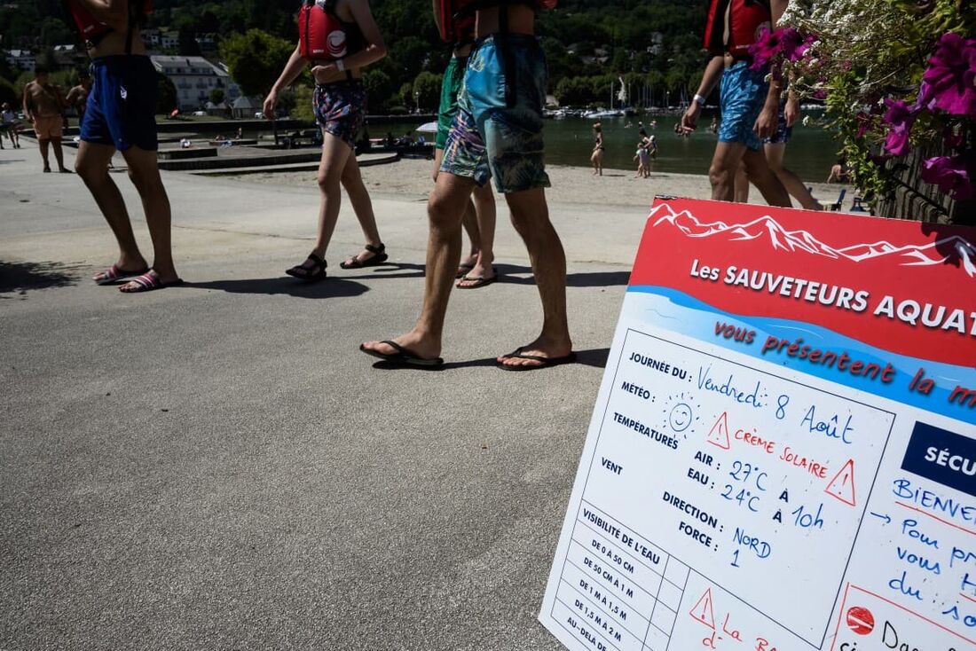 Pessoas passam por uma placa indicando as temperaturas perto da praia do lago Le Bourget, em Le Bourget-du-Lac, centro-leste da França.