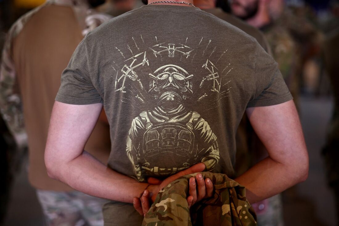 Um soldado ucraniano veste uma camiseta com a imagem de um militar cercado por drones durante um evento de celebração do Dia da Independência da Ucrânia