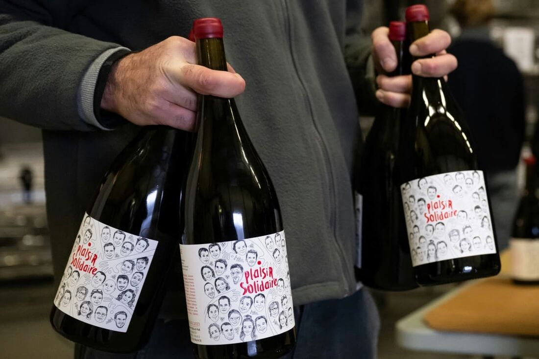 membros da associação de viticultores "Rouge Provence" segurando garrafas magnum enceradas e rotuladas de um vinho tinto chamado "United Pleasure"