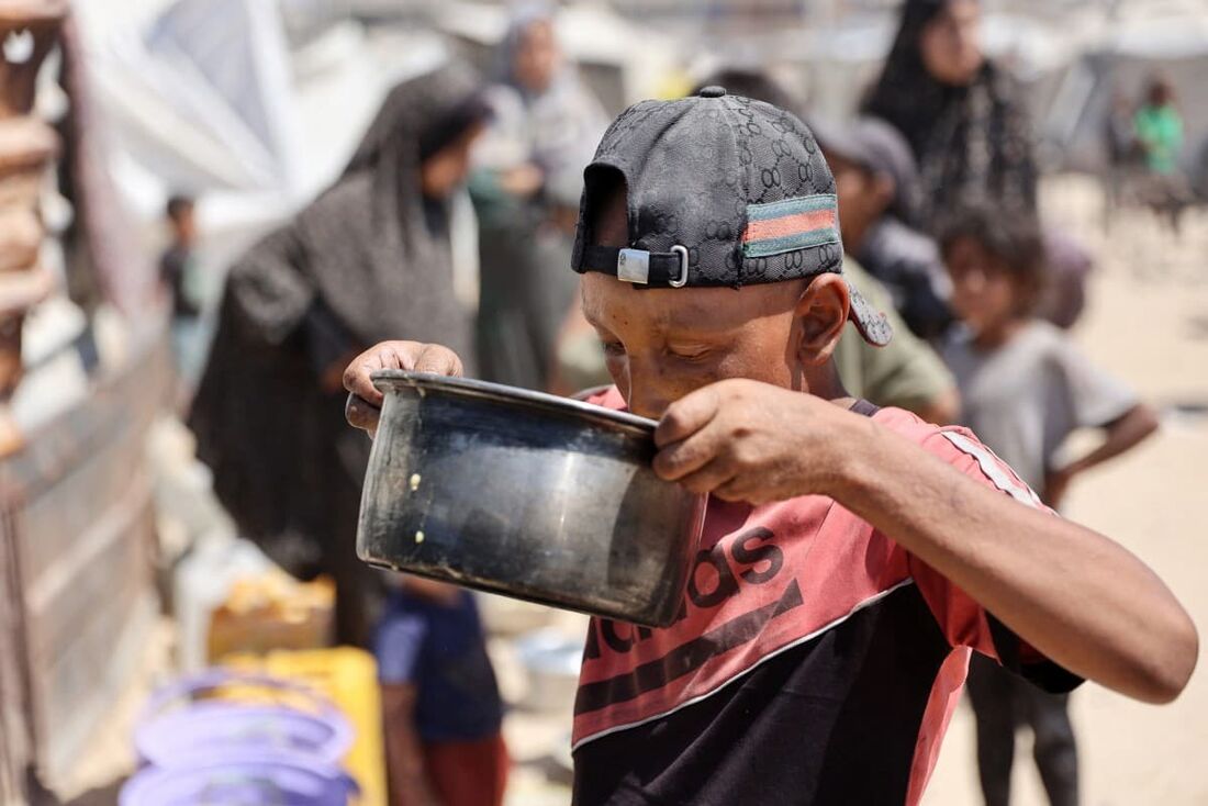 Um menino palestino bebe sopa de lentilha que obteve em um ponto de distribuição de alimentos na Cidade de Gaza em 1&ordm; de agosto de 2025.