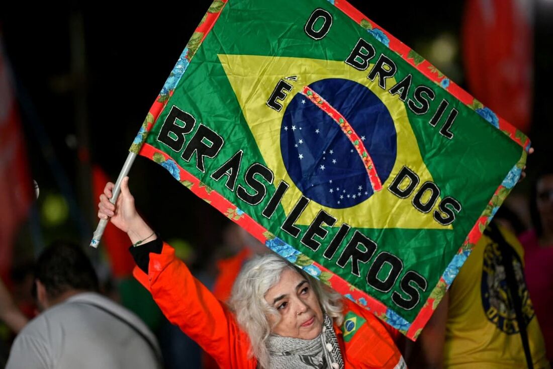 Uma mulher hasteia uma bandeira brasileira feita à mão com os dizeres "O Brasil é para os brasileiros" durante um protesto em defesa da soberania nacional após tarifas e sanções comerciais impostas pelo governo dos EUA ao Brasil.