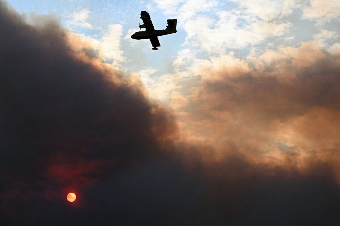 Canadair da segurança civil francesa voando enquanto o sol está escondido pela fumaça densa durante um incêndio florestal perto de Fontjoncouse, sudoeste da França, em 6 de agosto de 2025.