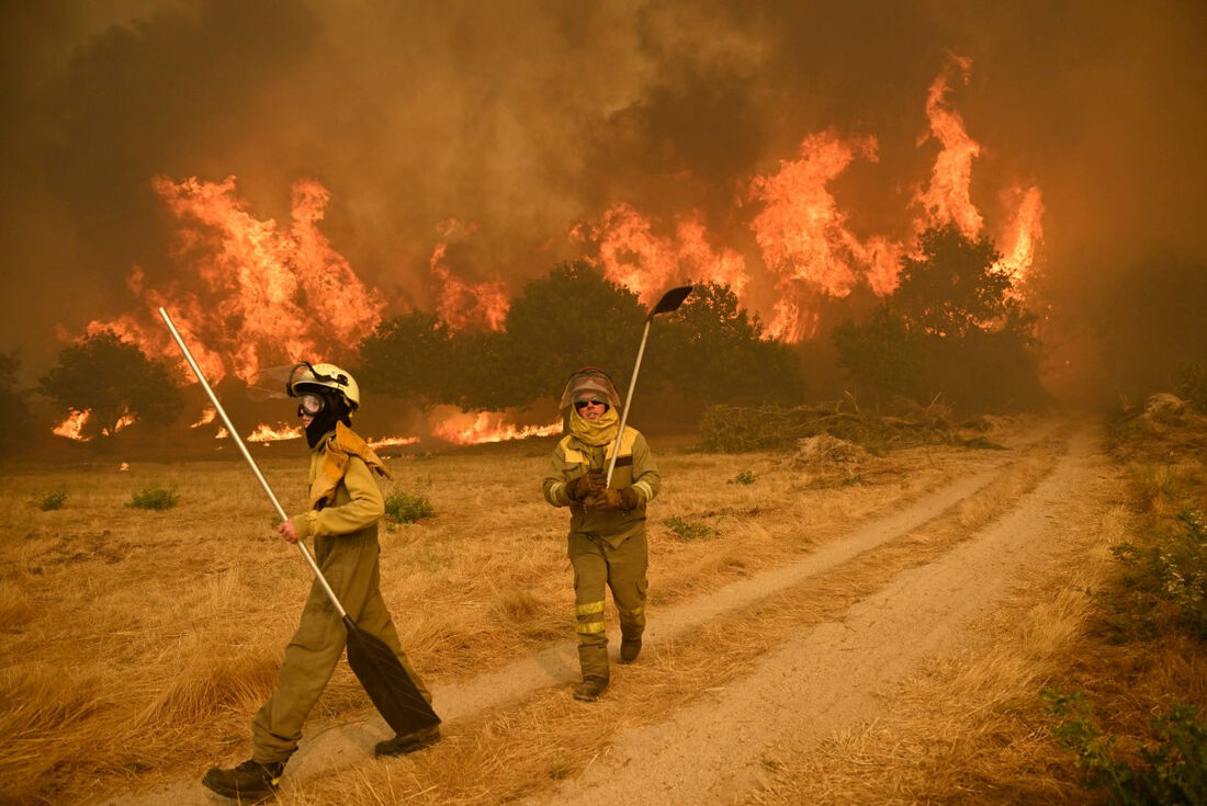 Moradores tentam combater um incêndio florestal na vila de Santa Baia de Montes, na província de Ourense, noroeste da Espanha, em 14 de agosto de 2025.