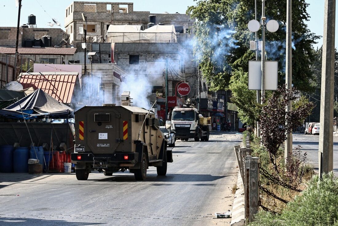 Um veículo militar israelense dispara gás lacrimogêneo durante um ataque ao campo de refugiados de Al-Amari, perto de Ramallah, na Cisjordânia ocupada