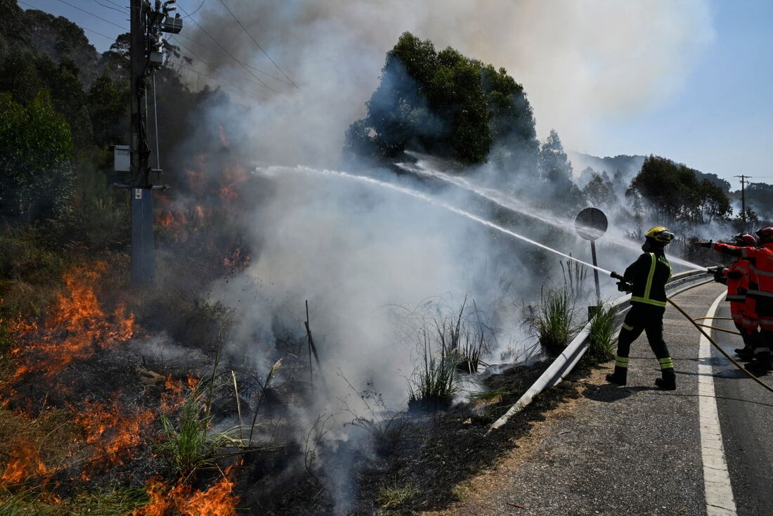 Bombeiros tentam controlar um incêndio florestal perto da vila de Mougas, no município de Oia, noroeste da Espanha, em 22 de agosto de 2025.