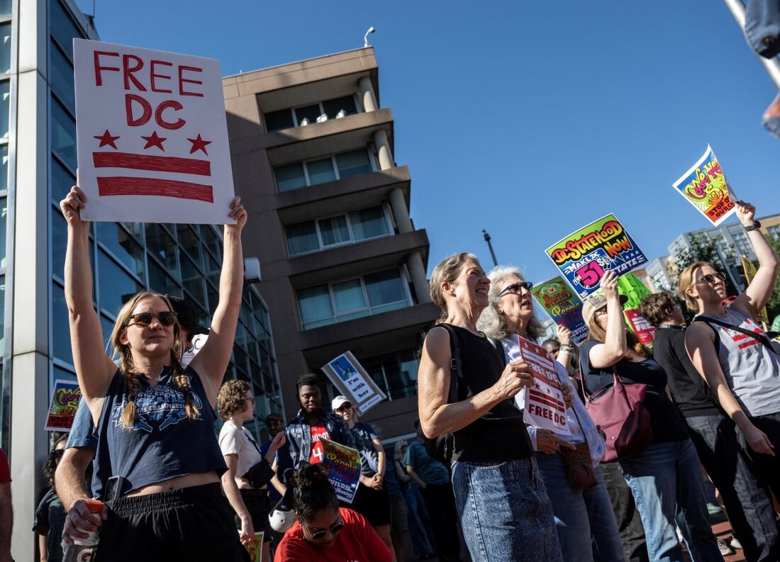 Manifestantes seguram cartazes durante uma manifestação contra o envio da Guarda Nacional e o aumento das batidas de imigração em Washington