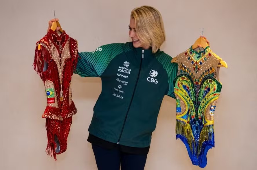 Camila Ferezin, técnica do conjunto da GR, exibe os novos collants para o Mundial da modalidade, que será no Rio de Janeiro; Foto: MeloGym/CBG 