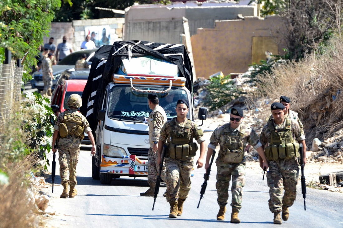 Soldados do exército libanês montam guarda enquanto um caminhão carregado de armas deixa o campo de refugiados palestinos de Beddawi, perto da cidade de Trípoli