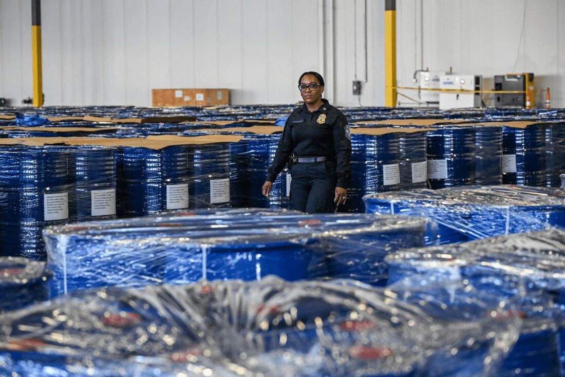 Um agente da Alfândega e Proteção de Fronteiras dos EUA caminha entre barris com produtos químicos usados para criar drogas sintéticas como a metanfetamina