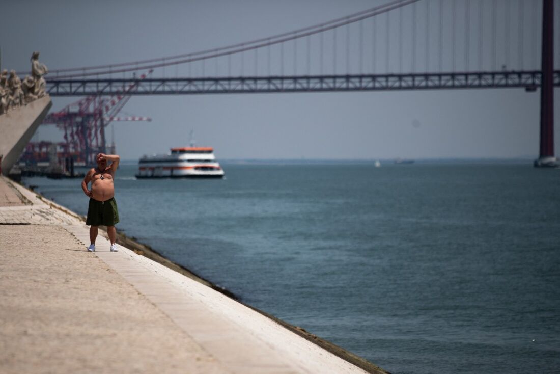 m homem sem camisa busca alívio do calor ficando perto do rio Tejo durante a primeira onda de calor do ano, em Lisboa.