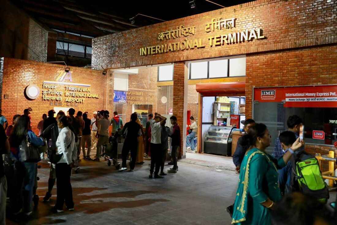 Passageiros se reúnem na entrada do Aeroporto Internacional de Tribhuvan, reaberto em Katmandu em 10 de setembro de 2025, após o fechamento devido a conflitos civis na capital do Nepal. 