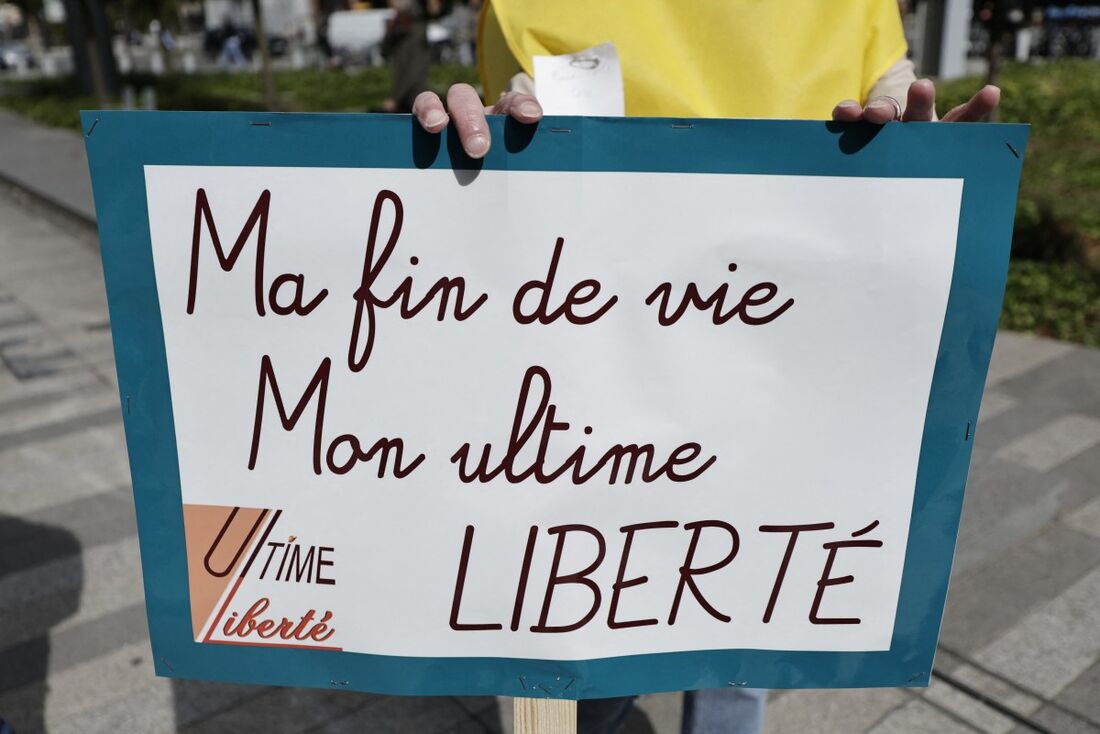 Um manifestante segura um cartaz com os dizeres "O fim da minha vida, minha liberdade final" durante uma reunião em apoio a 12 ativistas da morte assistida na abertura do julgamento