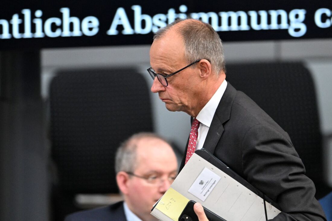 O chanceler alemão Friedrich Merz segura pastas ao sair de uma sessão do Bundestag (câmara baixa do parlamento) durante um debate geral sobre orçamento