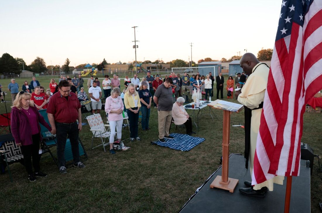 O pastor Georges Bidzogo (à direita) lidera uma vigília de oração do lado de fora da Igreja do Santíssimo Redentor em Burton, Michigan, em 28 de setembro de 2025, a poucos quilômetros de Grand Blanc, onde um atirador abriu fogo contra uma igreja mórmo