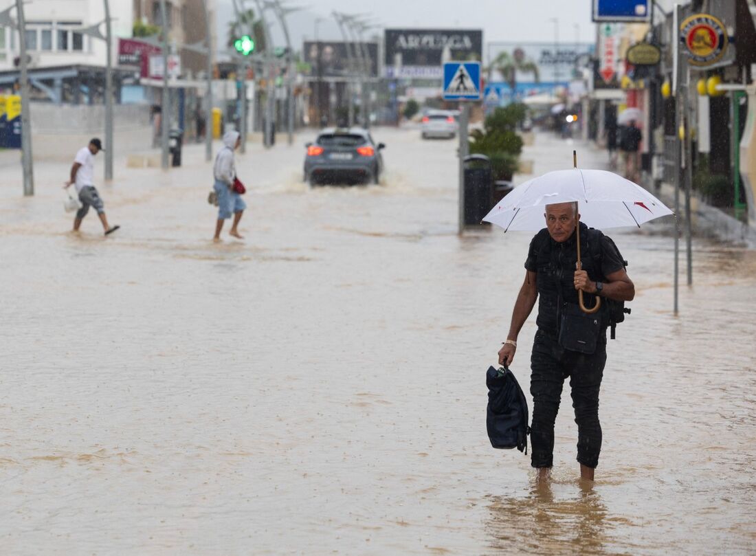 Pessoas caminham por uma rua inundada em Ibiza em 30 de setembro de 2025.