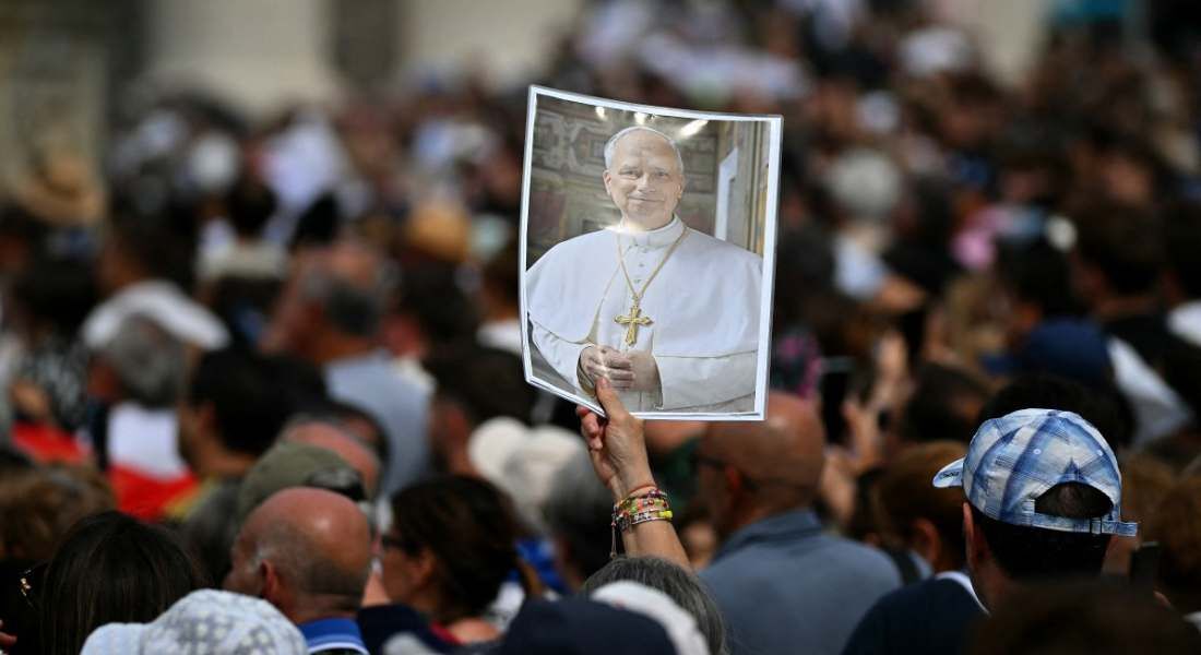 Peregrinos reunidos na Praça de São Pedro seguram uma imagem do Papa Leão XIV para lhe desejar um feliz 70º aniversário